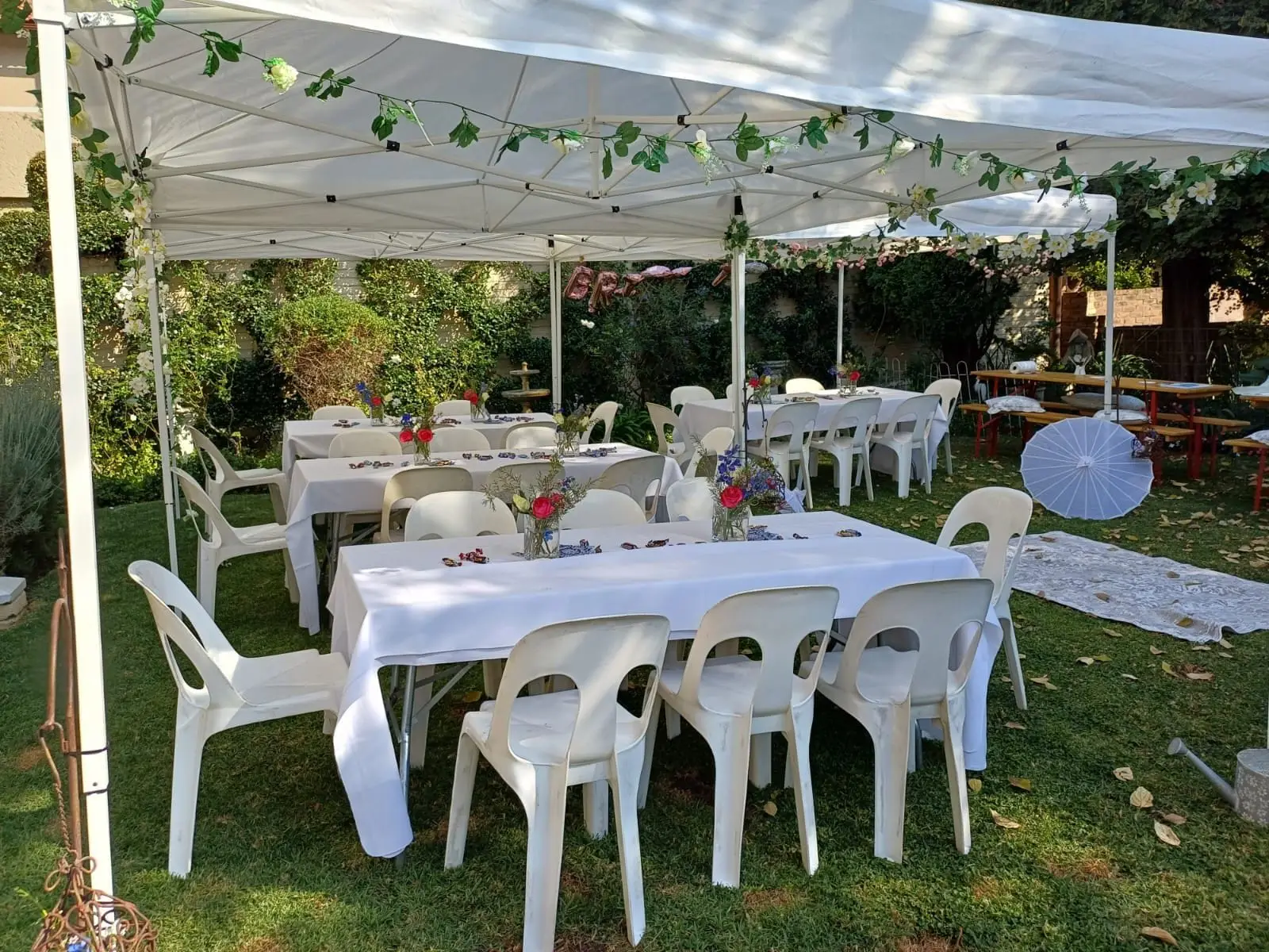 Outdoor event setup with tables, chairs, and floral decor.