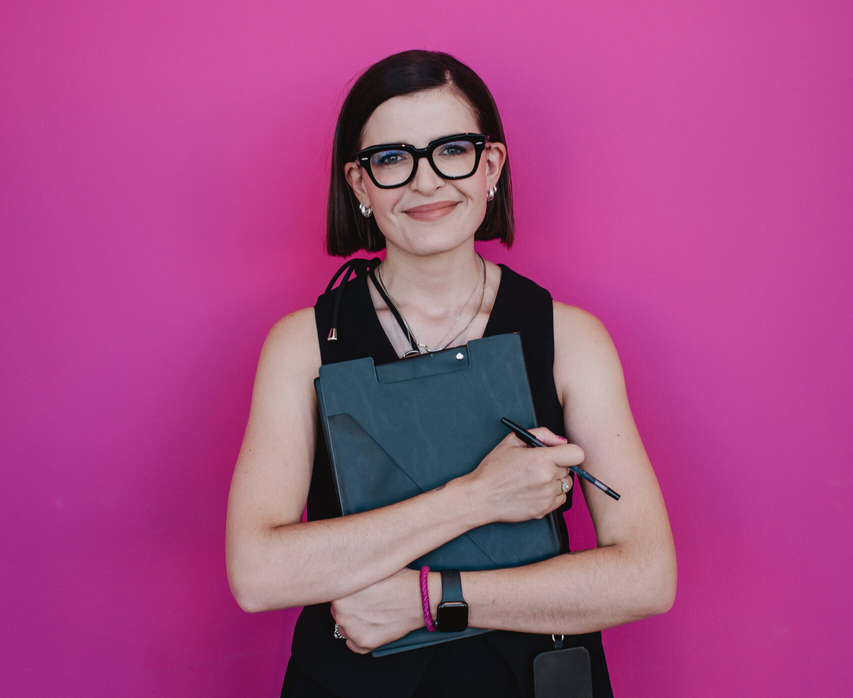 A team member holding a clipboard against a pink background