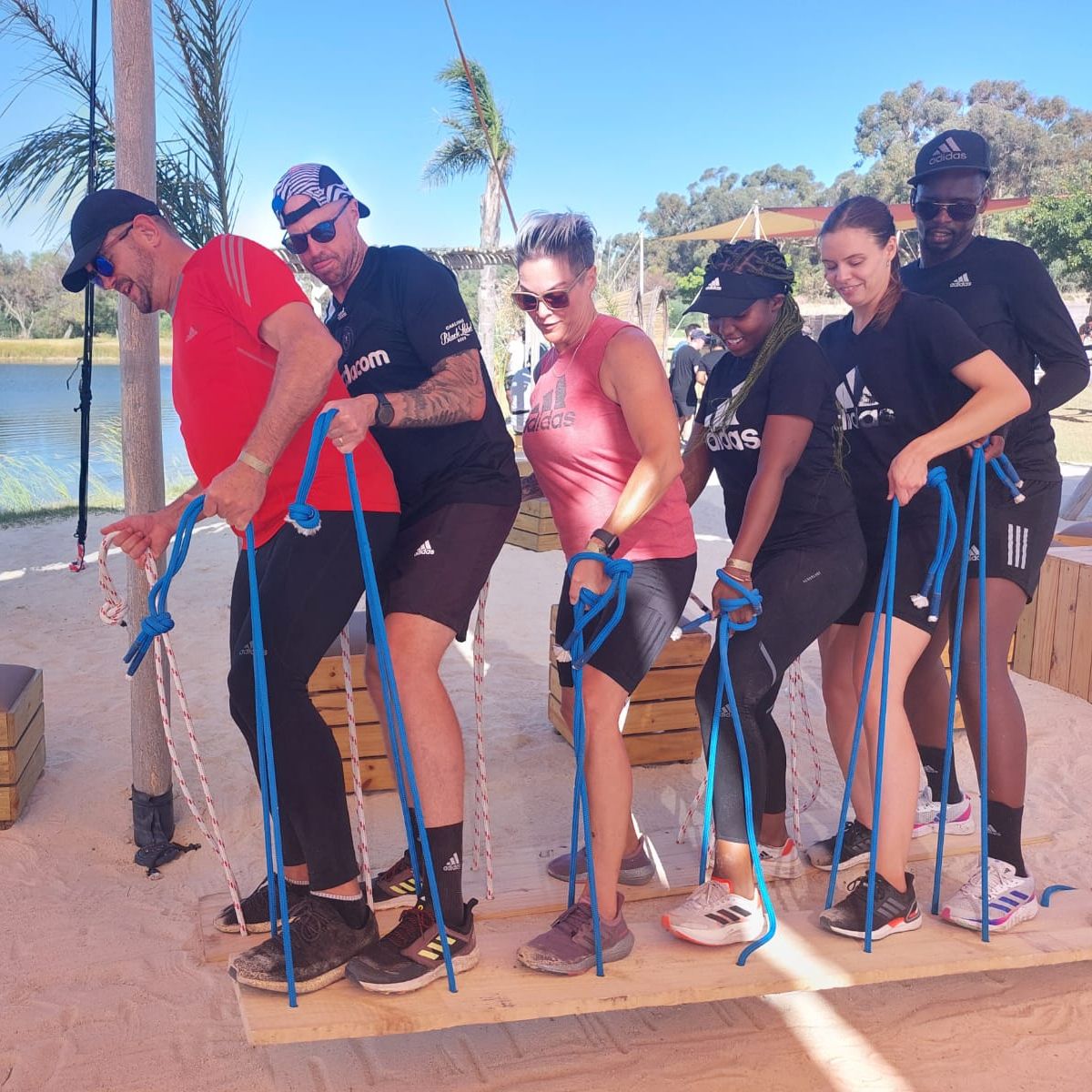 Participants engaged in a team building activity on a wooden plank at the beach