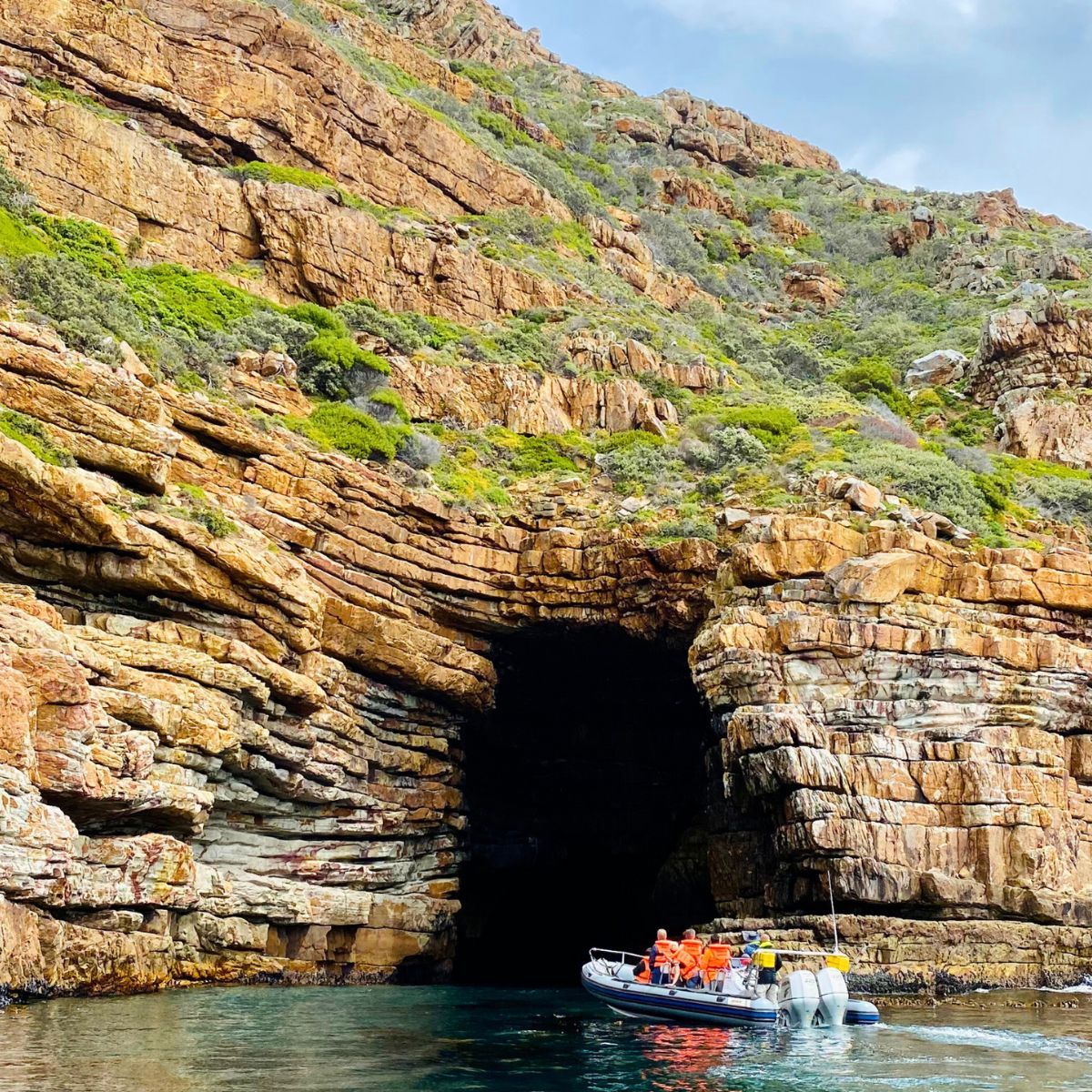 Boat navigating towards a coastal cave entrance