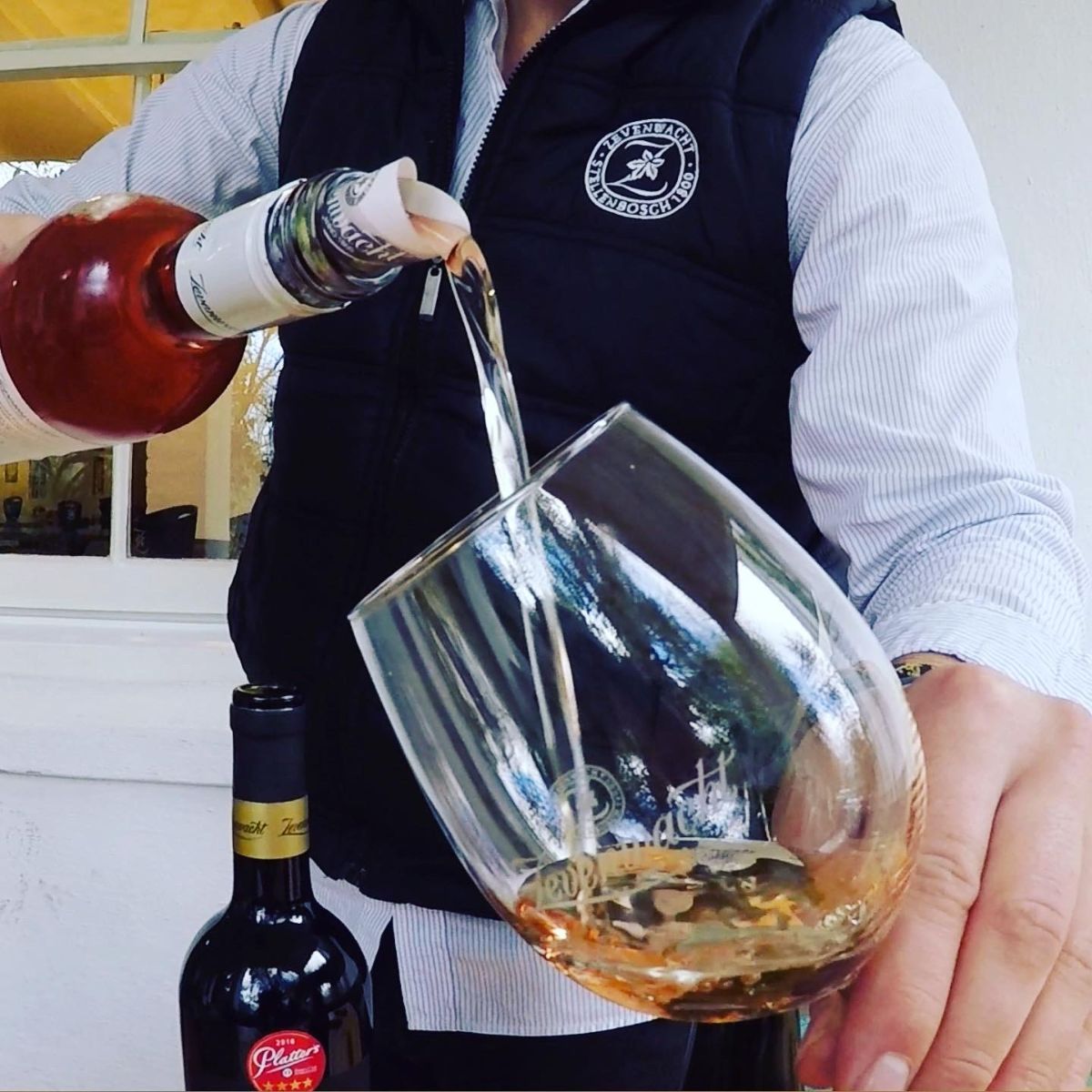 A glass of wine being poured from a bottle