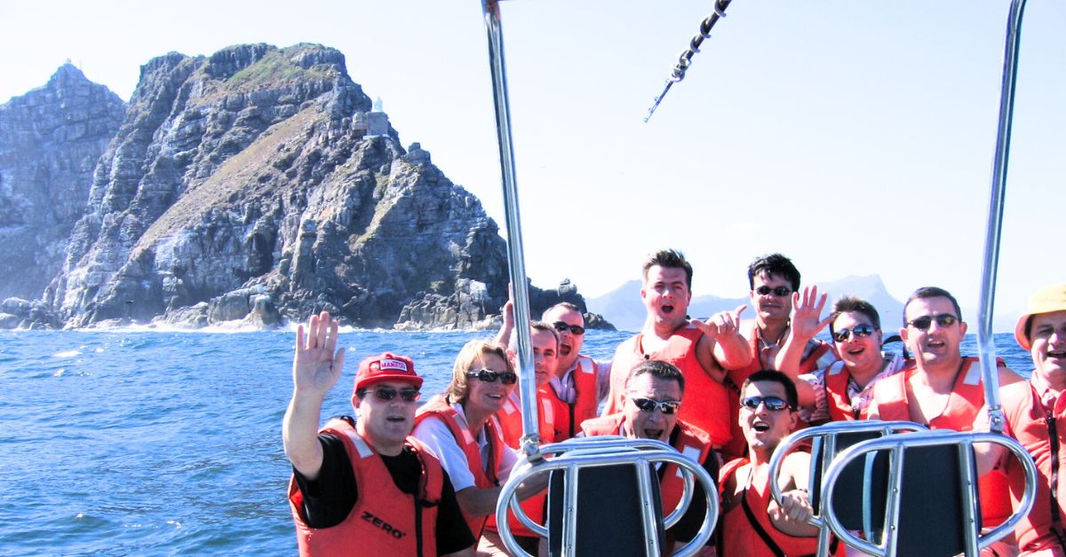 Group of people on a boat wearing life jackets near rocky coastline