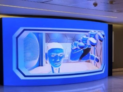 Large interactive holographic display featuring a robotic hand and human face.