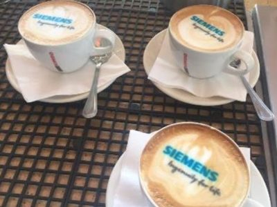 Three cappuccino cups with Siemens logo on top