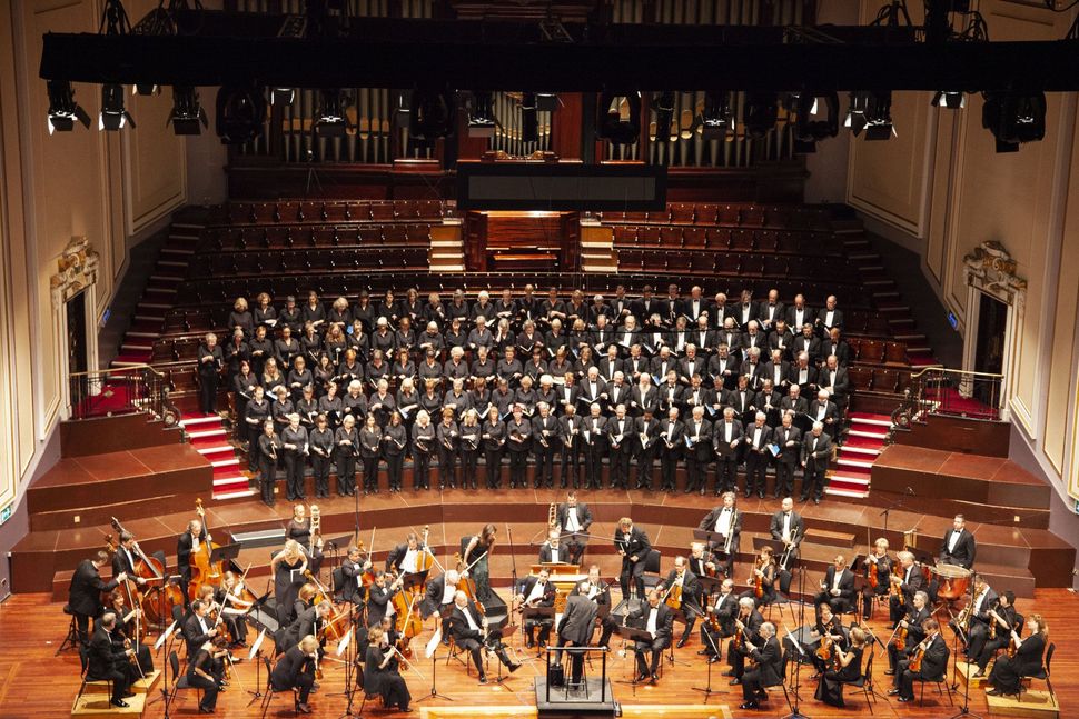 Full orchestra and choir performing on an ornate stage