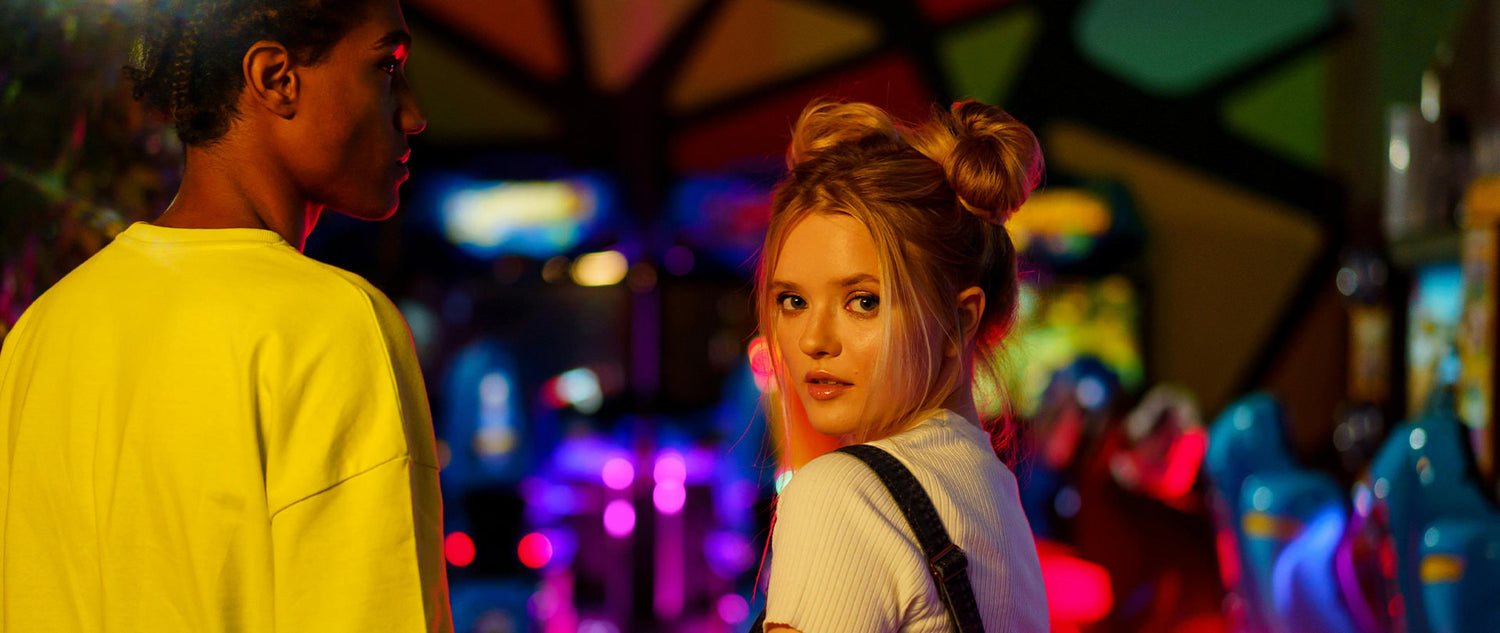 Two young adults in an arcade with colorful gaming machines