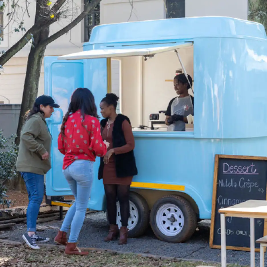 Blue dessert stall with customers and staff at an outdoor event.