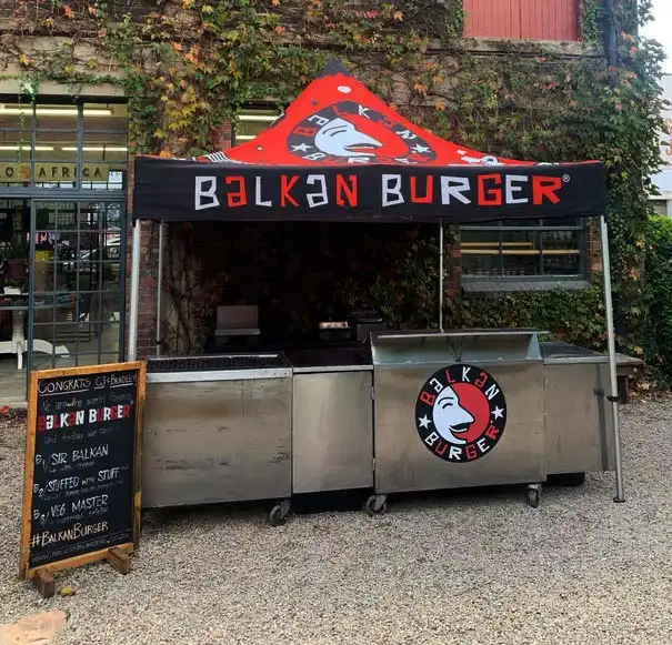 Balkan Burger food truck setup with canopy and stainless steel counters.
