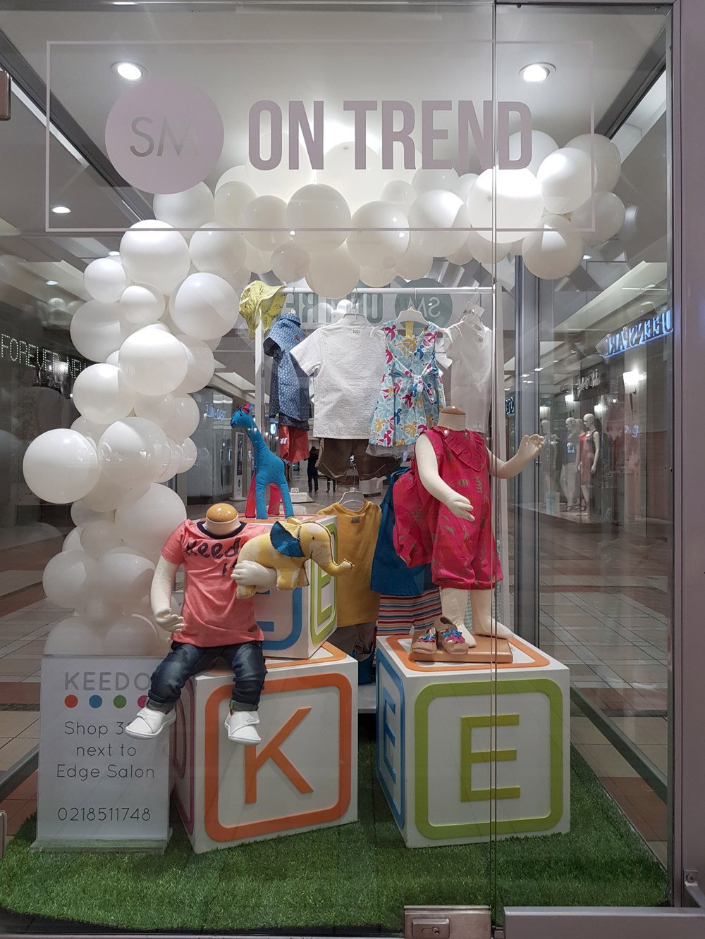 Retail display featuring balloons and clothing in a store window