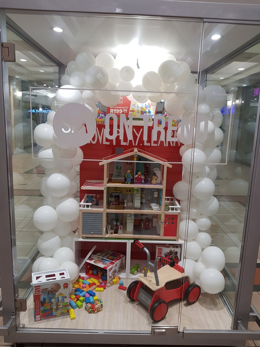 White balloon arch surrounding a toy display in a store.