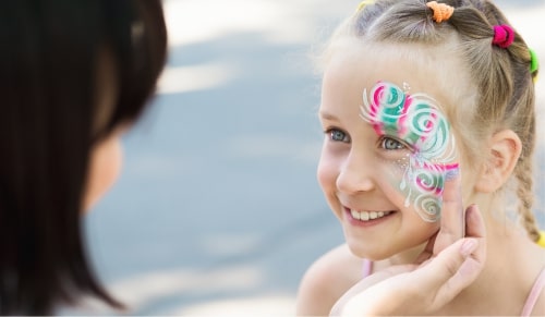 Child with colorful face paint smiling