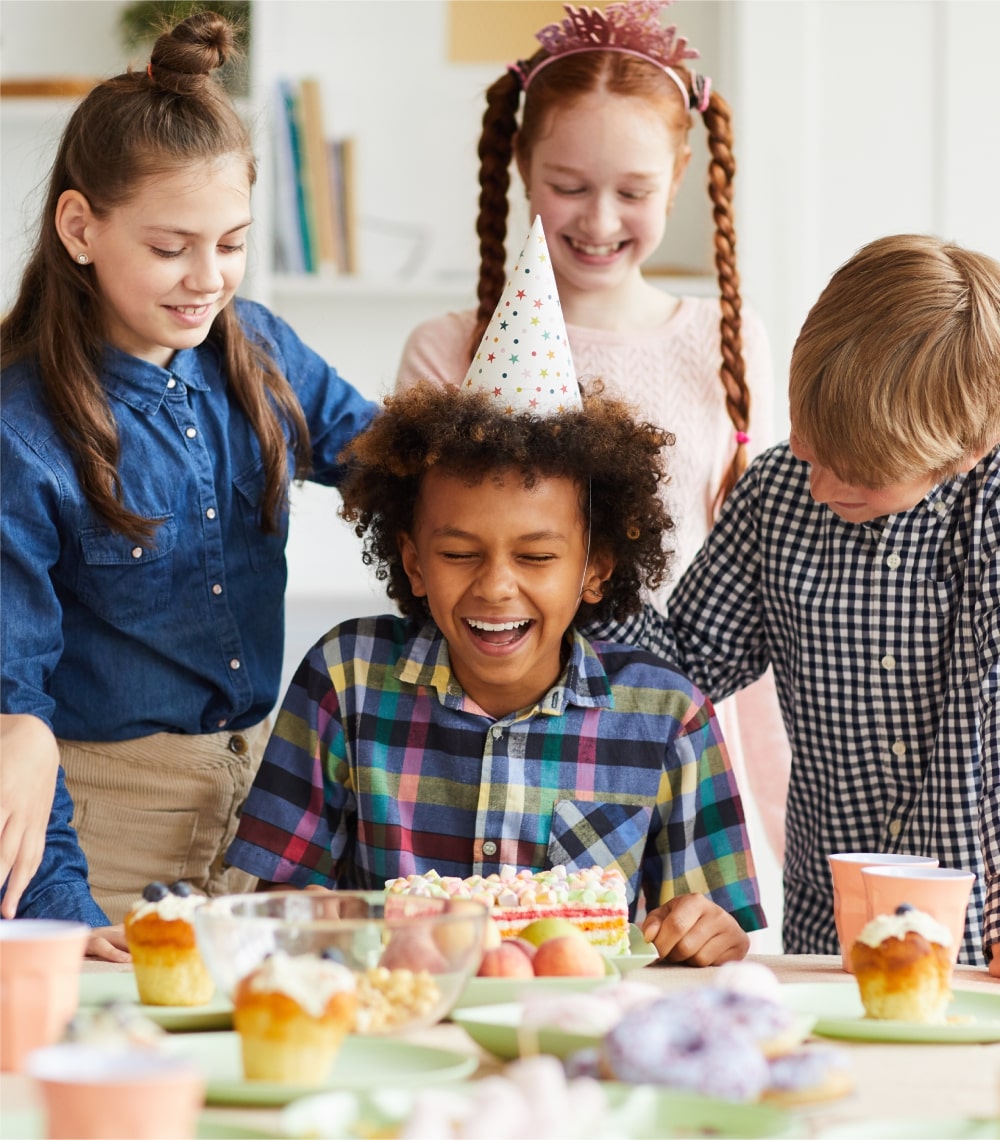 Children celebrating a birthday with cake and party hats.