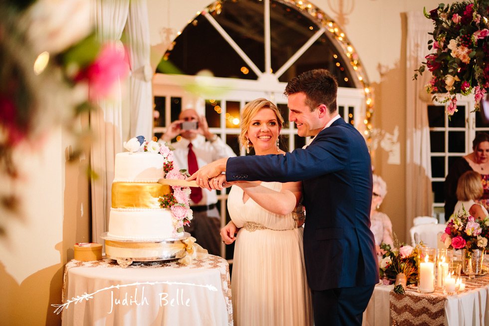 Bride and groom cutting wedding cake together