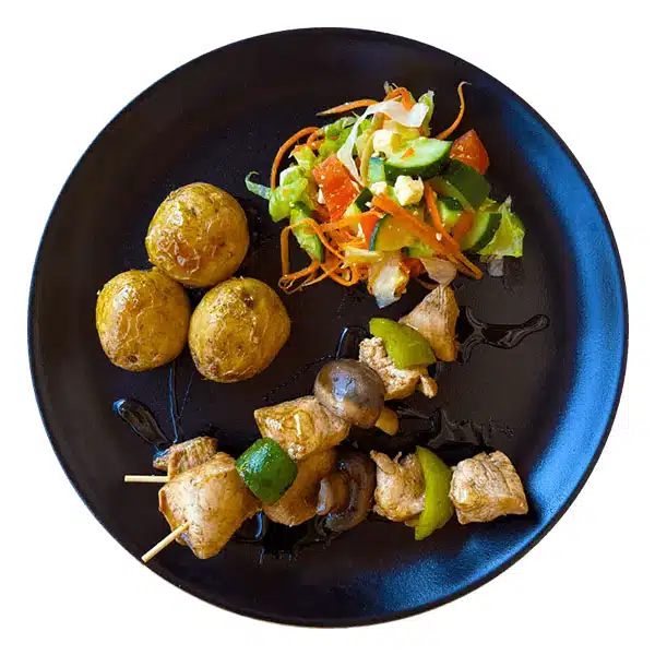 Platter featuring chicken skewers, potatoes, and salad