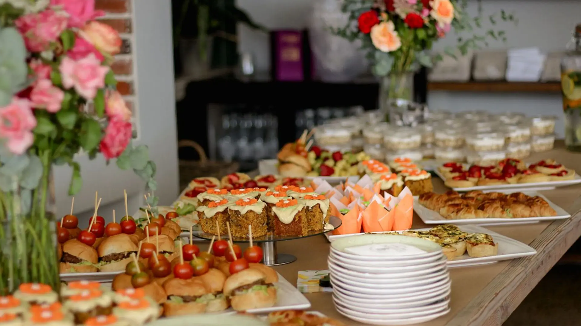Assorted gourmet food platter with sliders, salads, and desserts.