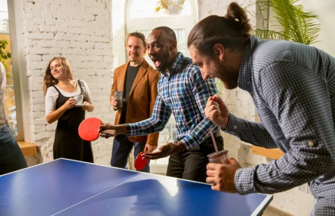 Group of people playing ping pong in a bright room