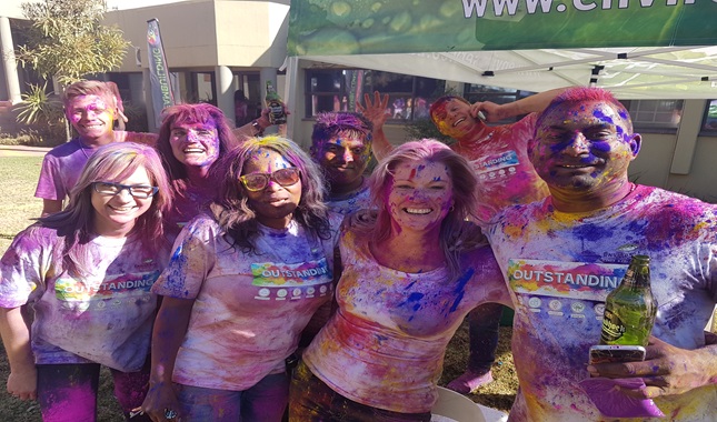 A group of people covered in colorful powder during a fun event.