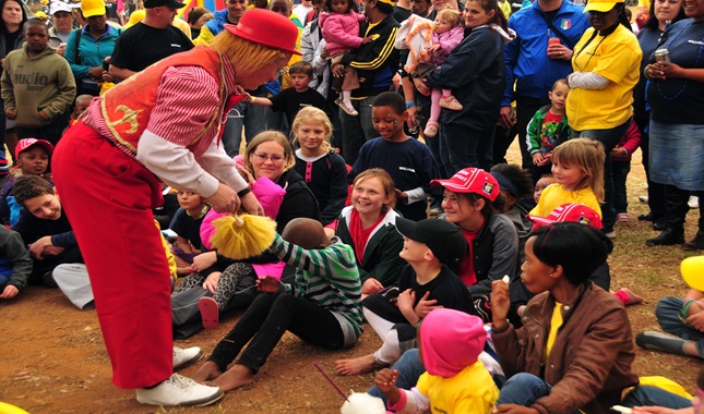 Clown entertaining children at a lively outdoor event.