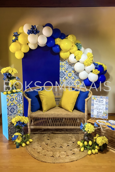 Colorful balloon backdrop with flowers and seating area.