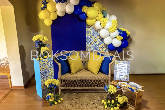 Colorful balloon backdrop with flowers and seating arrangement.