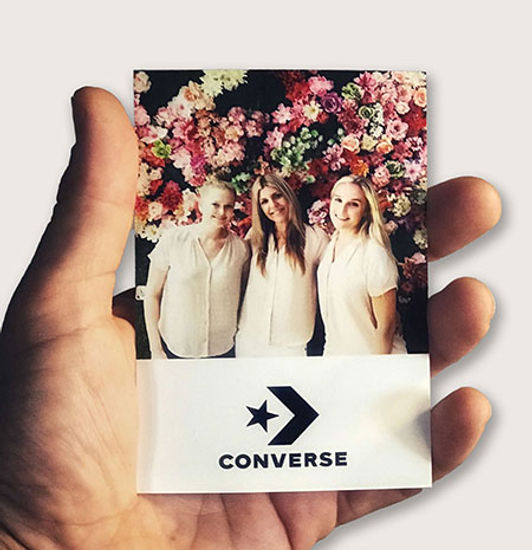 Photo of three people in front of flowers and a Converse logo