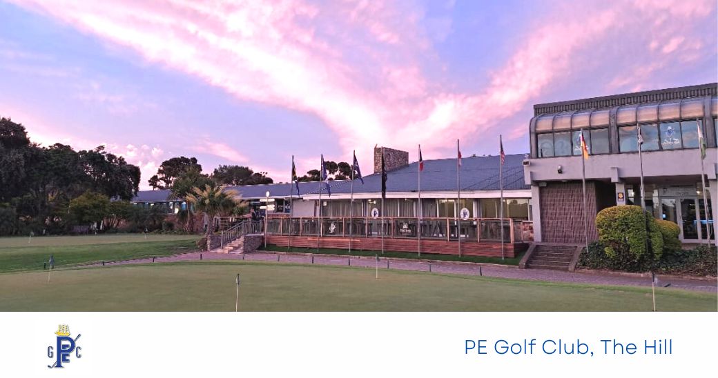 Exterior view of PE Golf Club with flags and a sunset sky