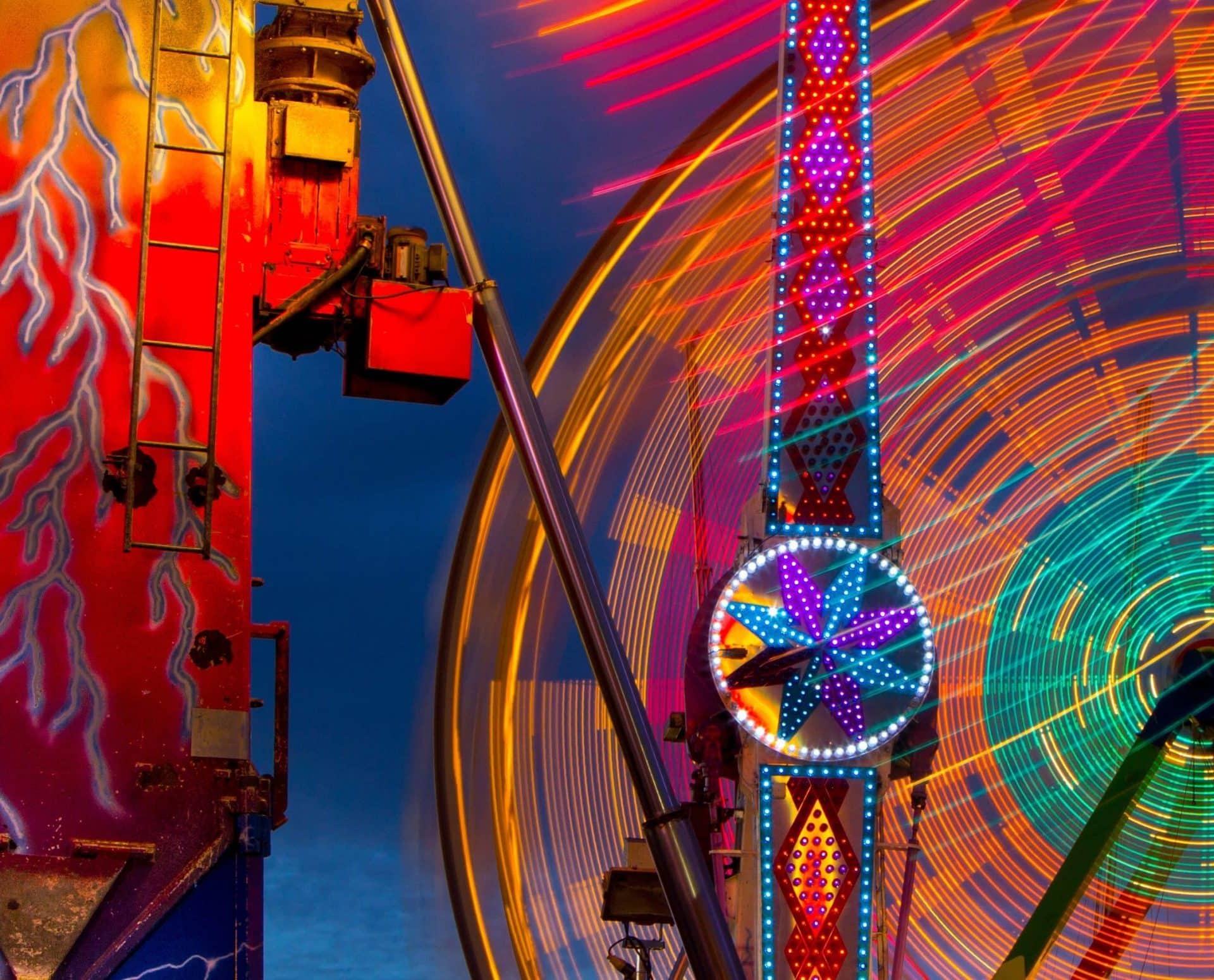 Colorful illuminated rides during setup.