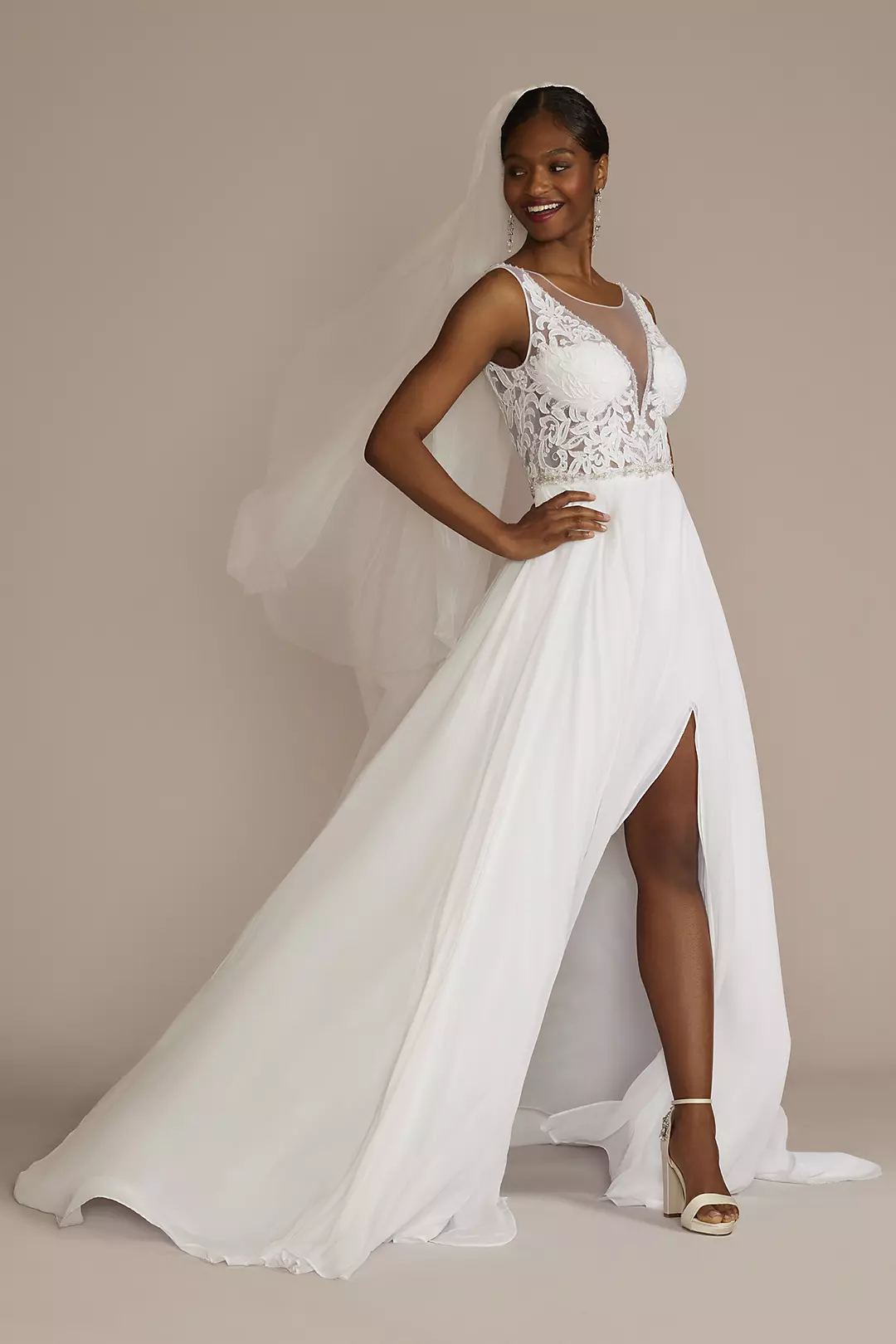 A model wearing an elegant bridal gown with a deep neckline and flowing skirt.