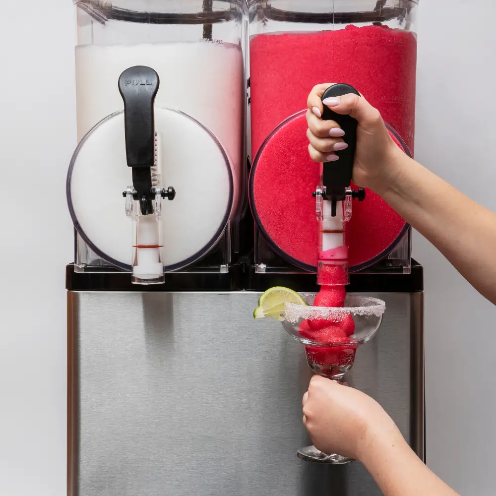 Hands pouring slush from a machine into a glass