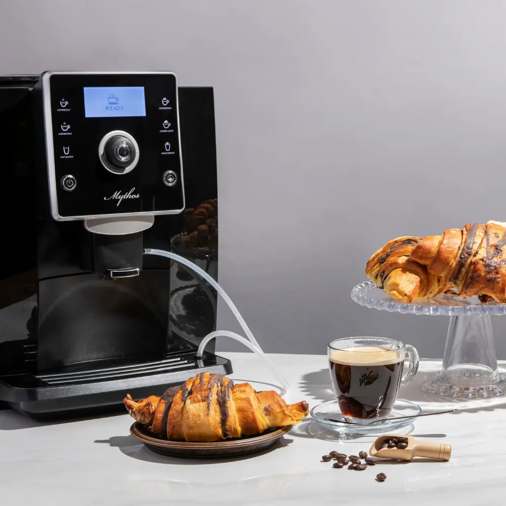 Coffee machine, croissant, and coffee cup arranged on a table