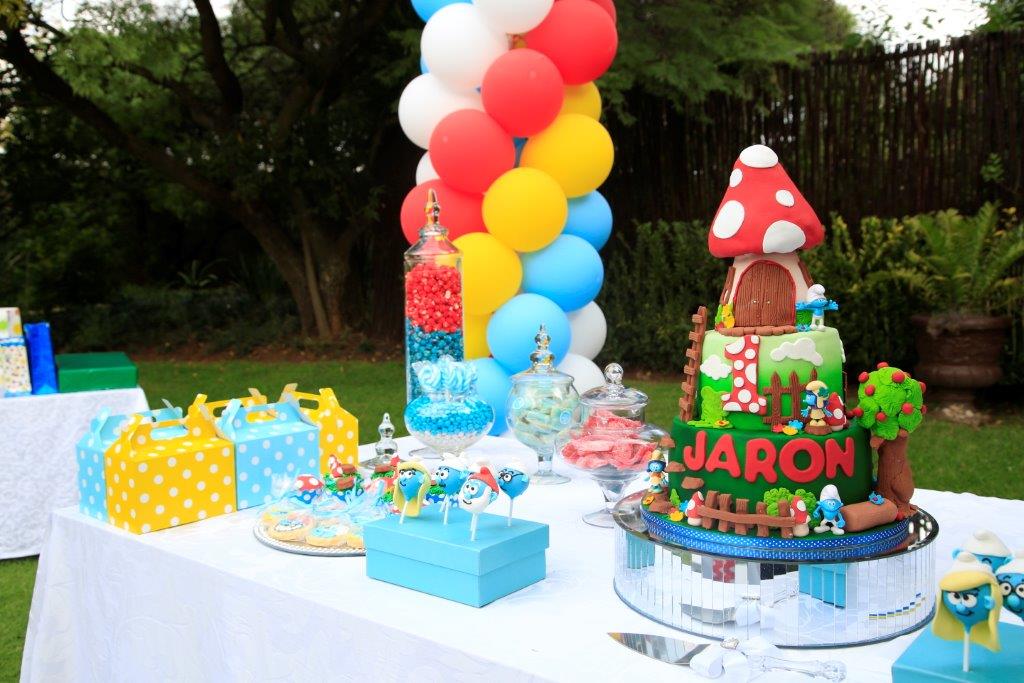 Outdoor birthday cake display with colorful sweets and decorations.