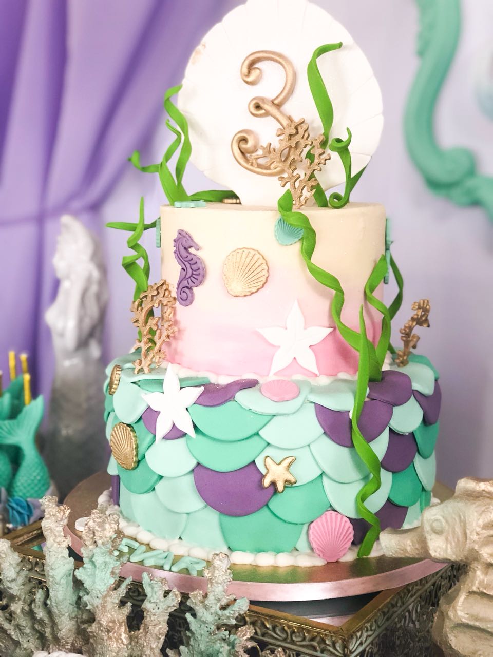 Two-tier mermaid-themed birthday cake with sea decorations.