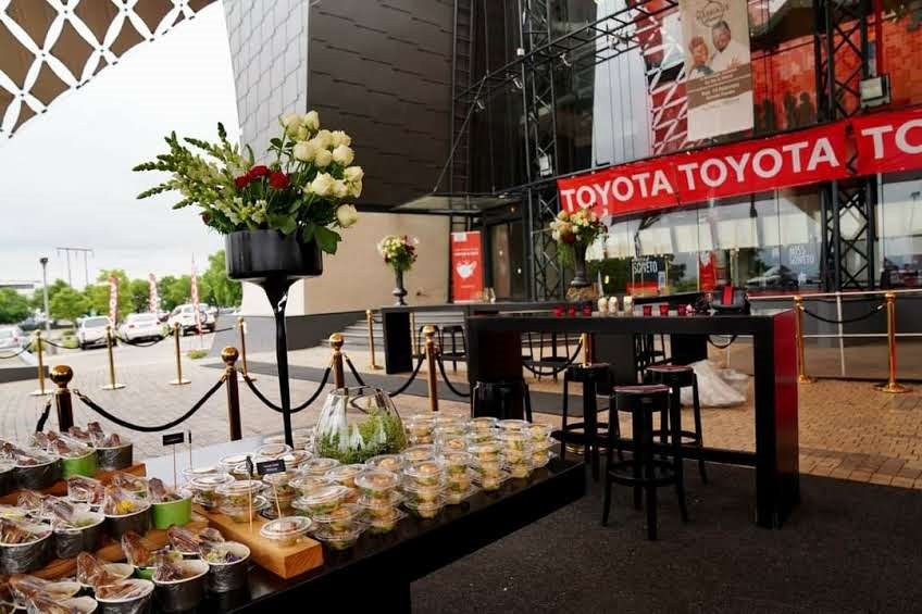 Catering setup with finger foods and floral arrangements outside a venue.