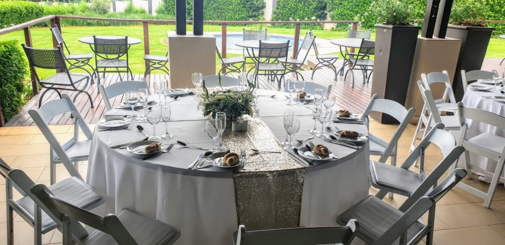Round table with white chairs set for dining outdoors