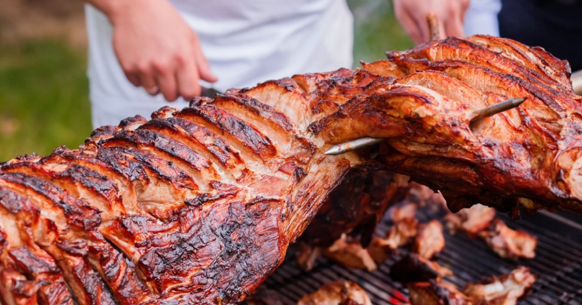 Whole lamb on a spit being grilled outdoors
