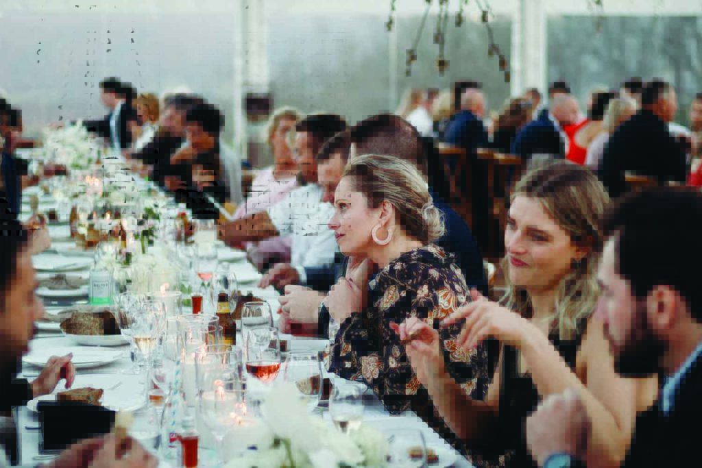Guests dining at a long table with floral decor.