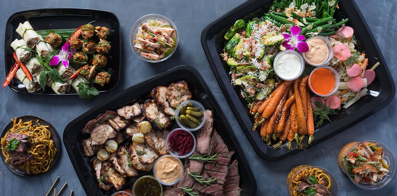 Buffet catering spread with various gourmet dishes on black trays.
