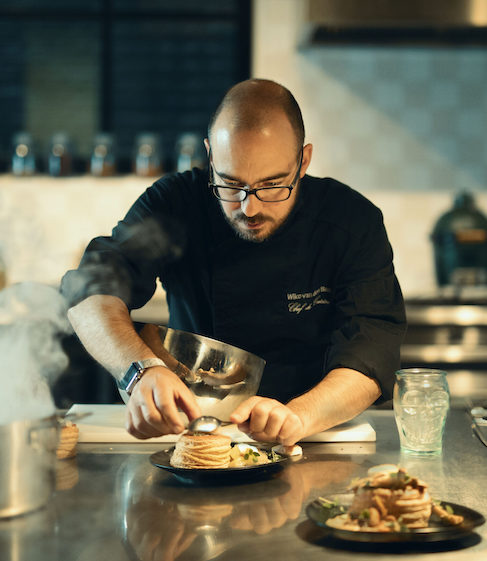Chef plating a vegan dish in a modern kitchen.