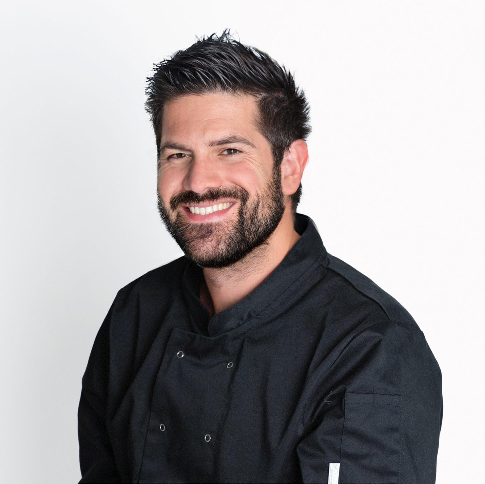 Smiling chef in a black uniform against a white background