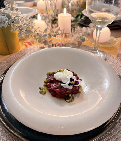 Gourmet beetroot tartare in a white dish with edible flowers