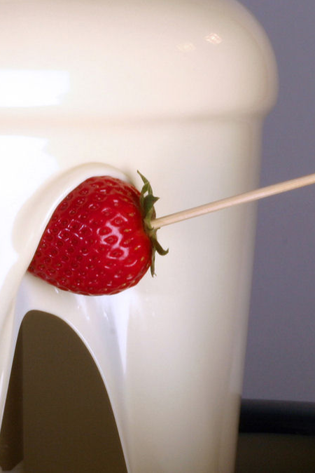 Strawberry on a skewer near a white chocolate fountain