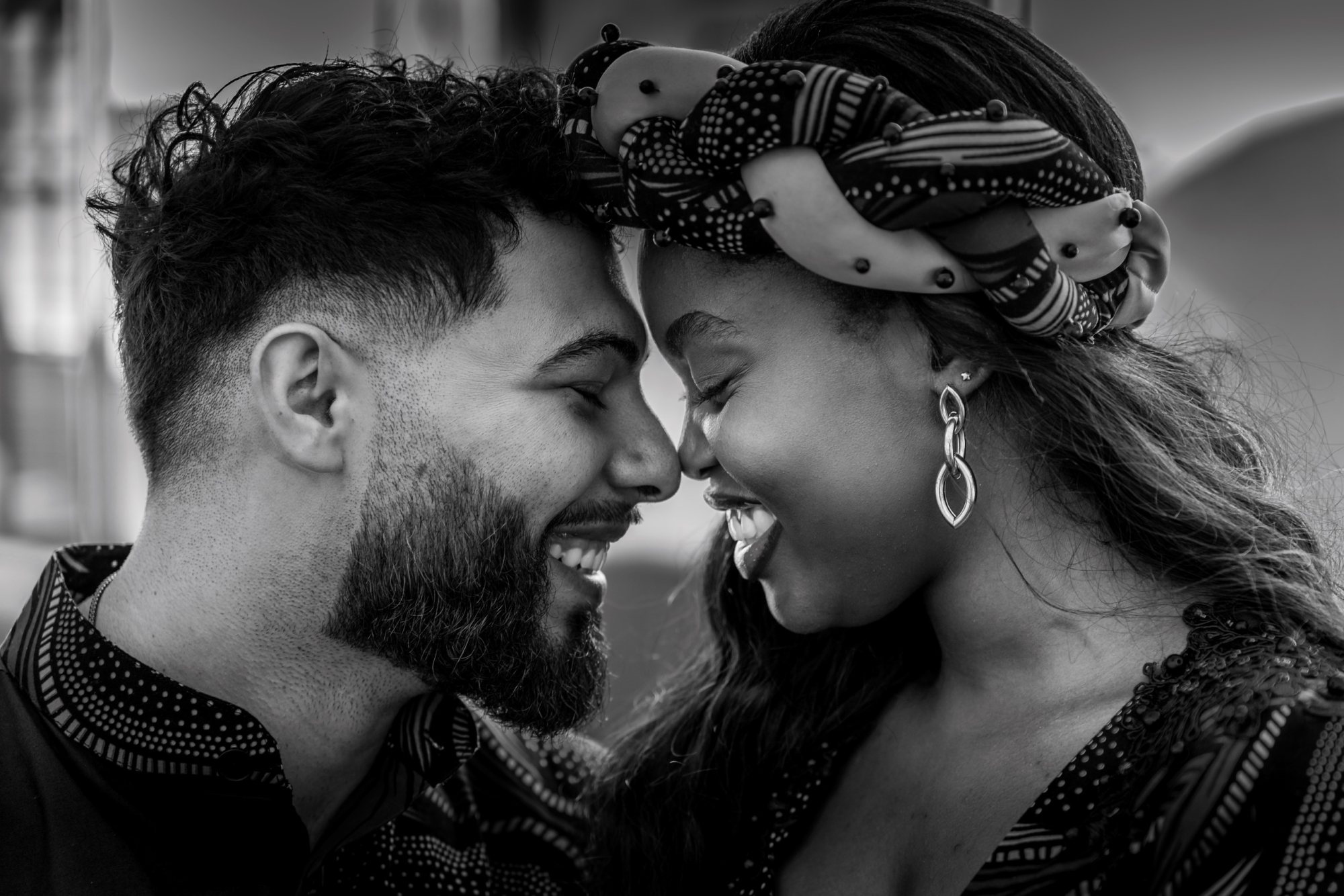 Black and white close-up of a couple smiling at each other.