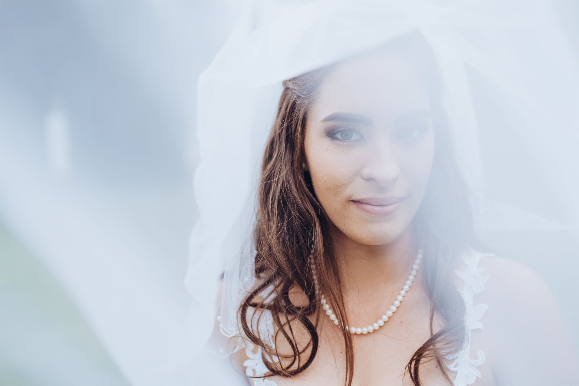Close-up of a bride wearing a veil and pearl necklace