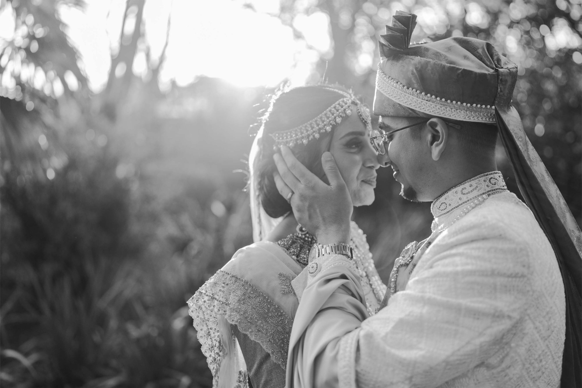 A couple embracing in a black and white photo during sunset