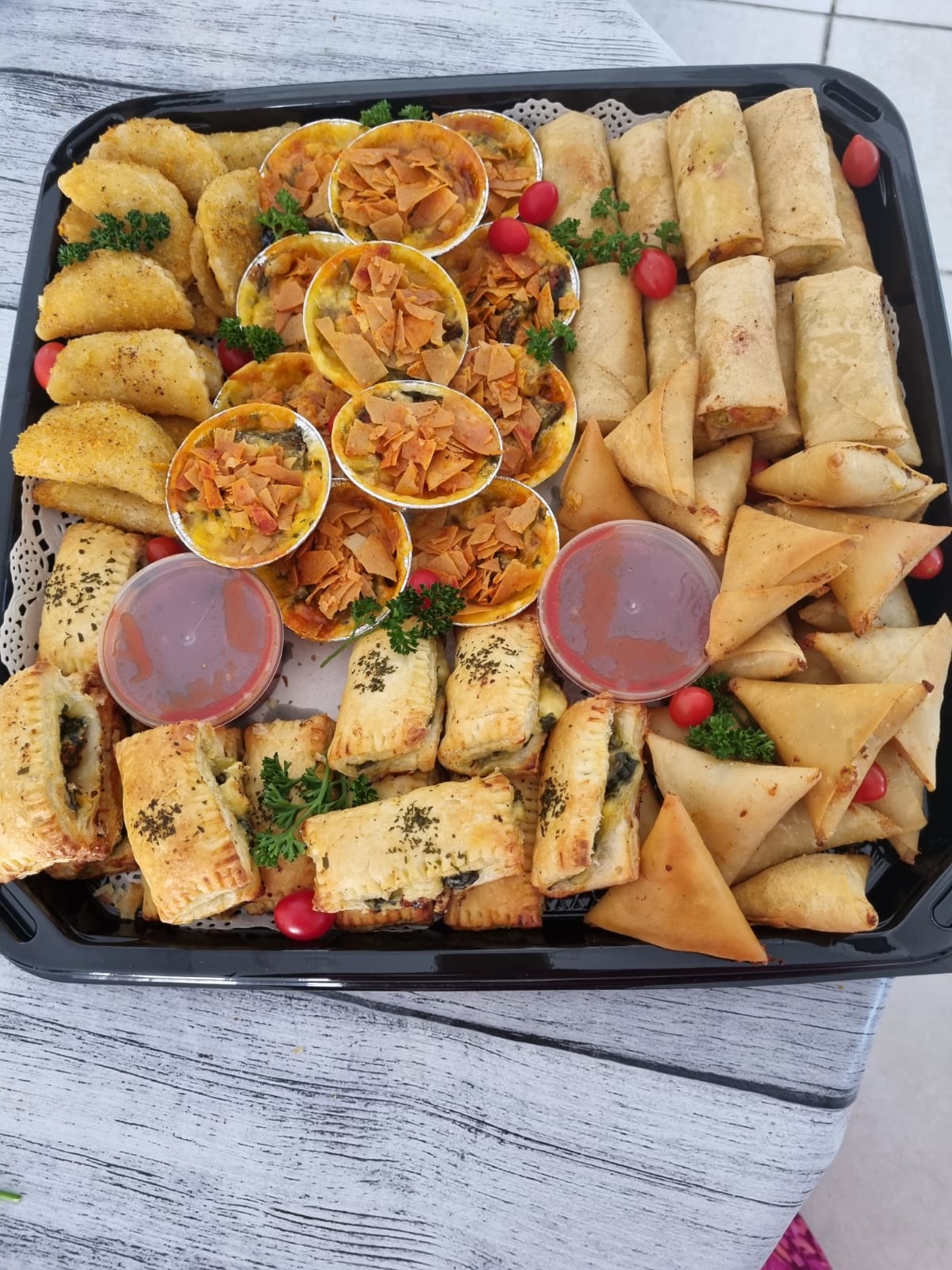 Tray of assorted savoury pastries and snacks with dipping sauces