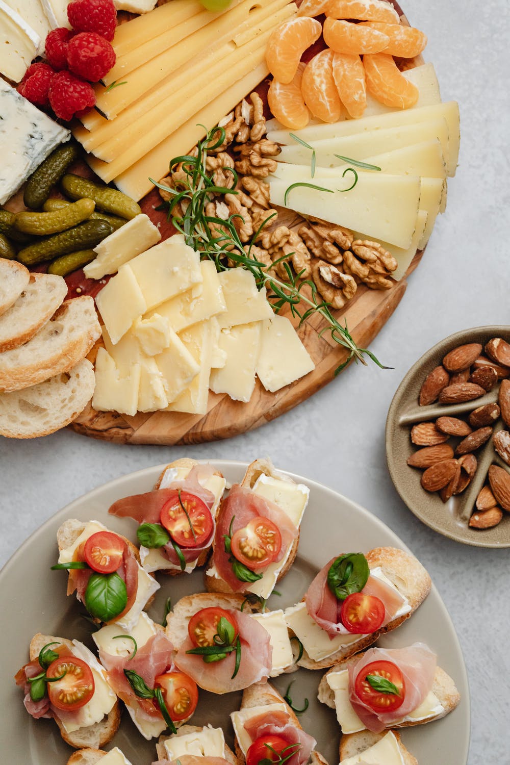 Cheese and deli platter with bread, fruits, and nuts