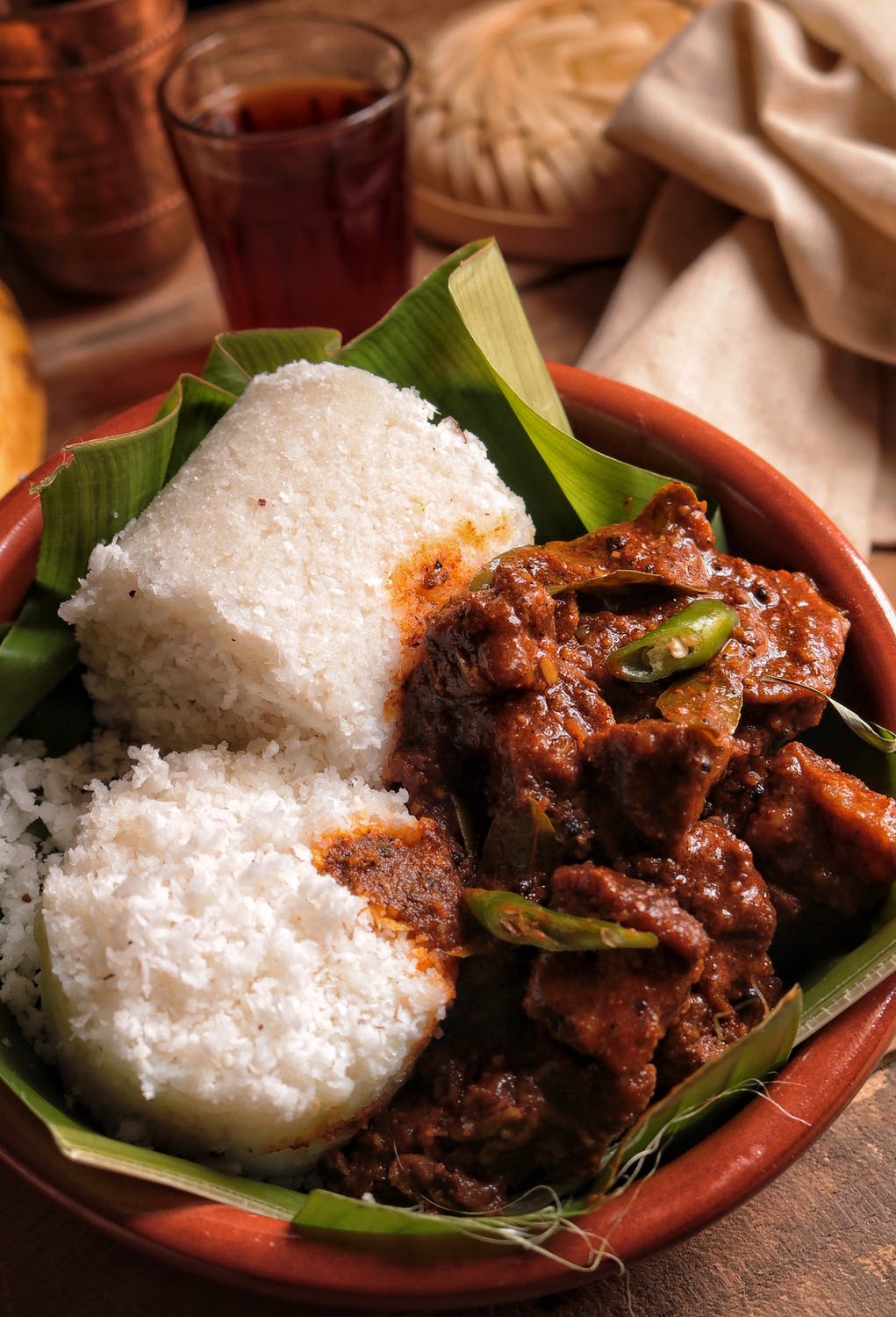 Bowl of meat stew with rice served on banana leaves
