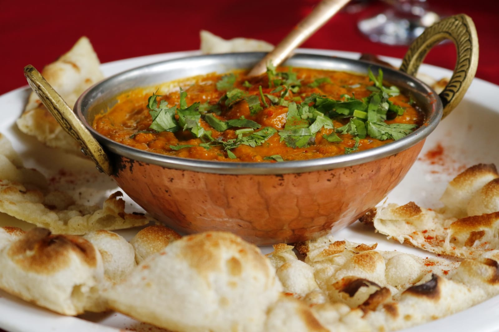 Bowl of chicken curry with naan on a plate