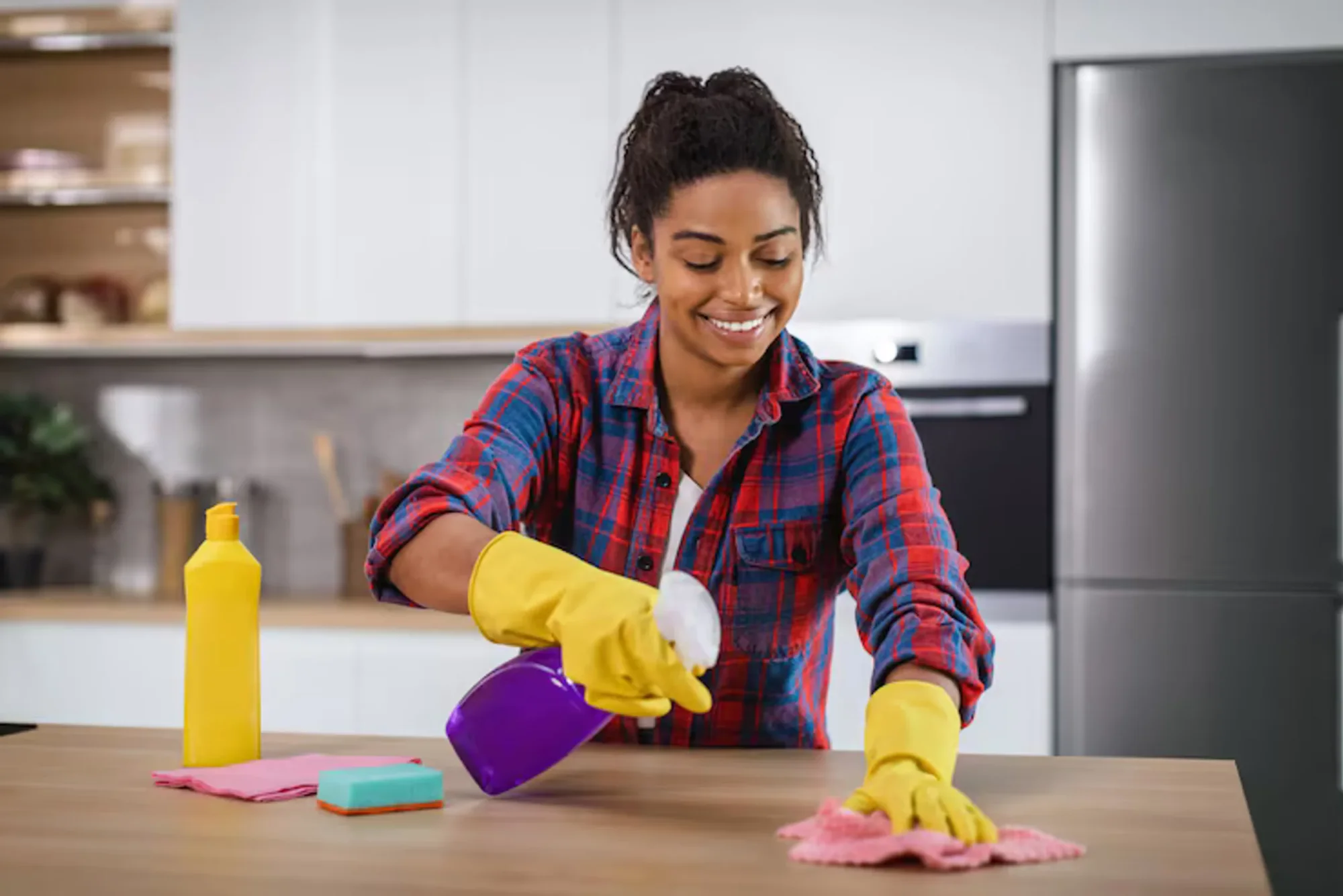 Woman in yellow gloves cleaning a kitchen counter