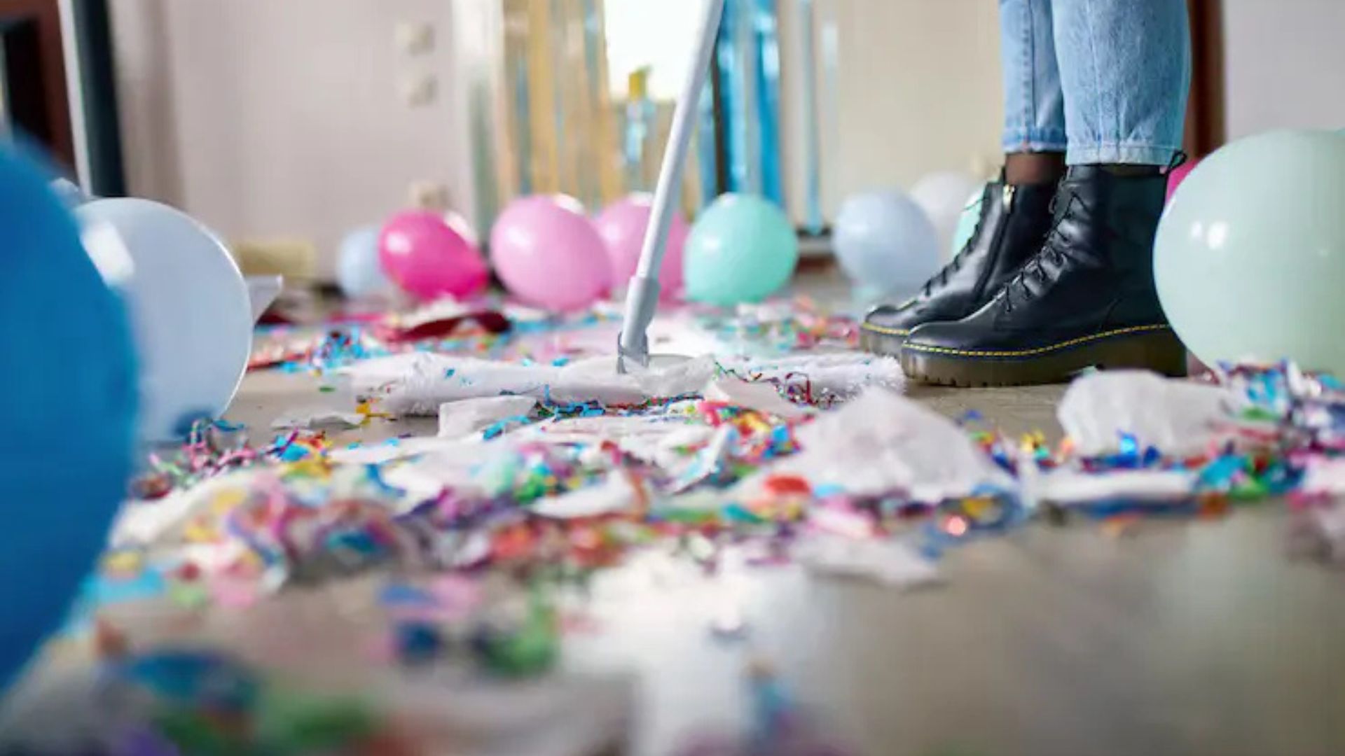 Person vacuuming a floor covered in party debris